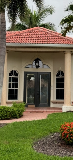 Arched impact windows and double entry doors on a stucco home