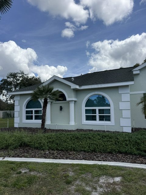 Modern hurricane impact windows: arched windows on both sides of the entry of a gray stucco home