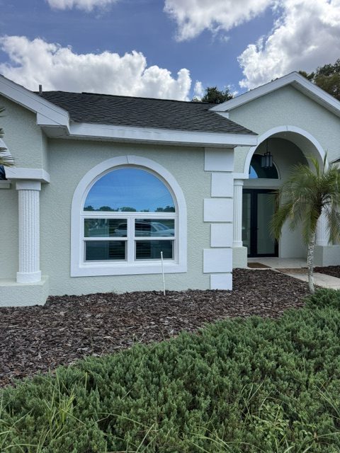Energy efficient windows: arched impact window on a stucco home