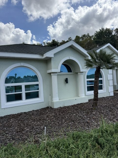 Benefits of hurricane impact windows: arched impact windows on a stucco home