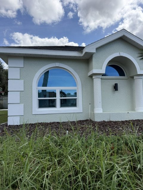Hurricane wind ratings for windows: arched impact window beside a front entry