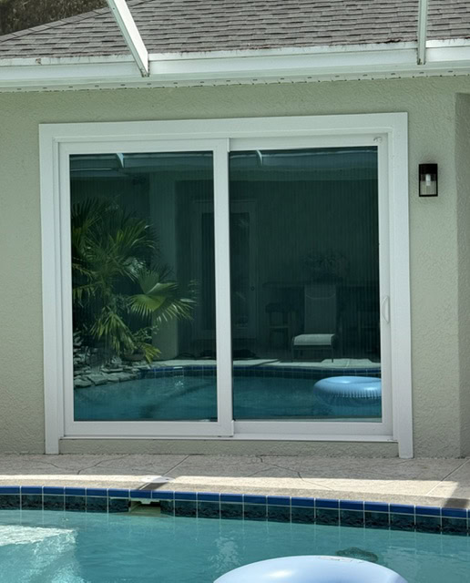 White-frame impact sliding glass door beside a pool
