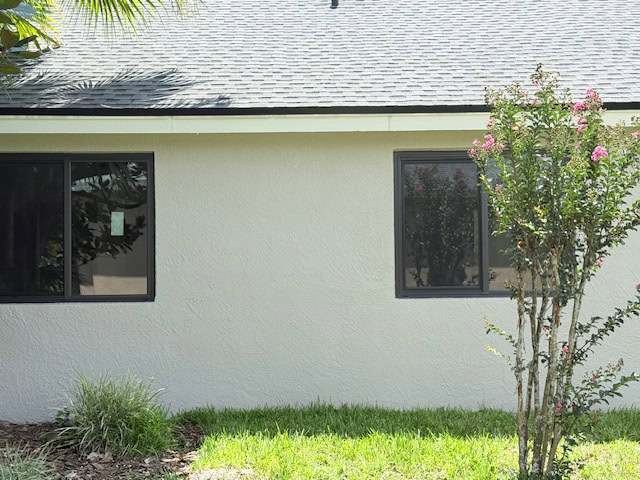 Corner of a stucco home with dark-frame impact windows