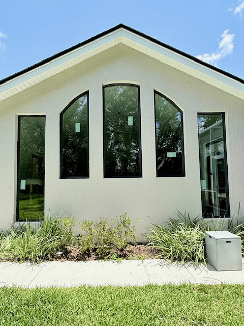 Impact window investment: arched gable impact windows on a stucco home