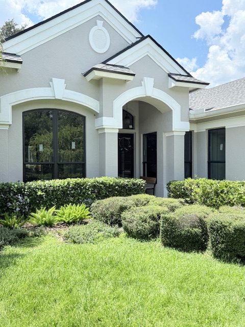 White stucco Florida home with arched impact entry doors and impact windows