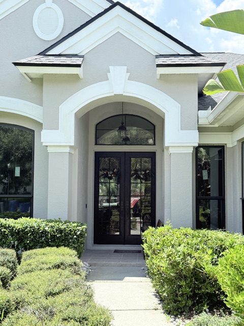 Arched impact entry doors with a transom on a white stucco Florida home, installed by Storm Pro