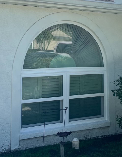 Window energy savings: arched impact window above interior shutters