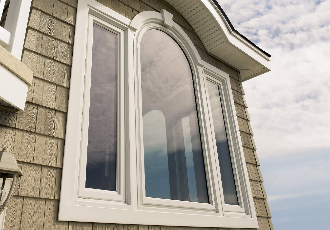Arched specialty shape impact window on a home exterior