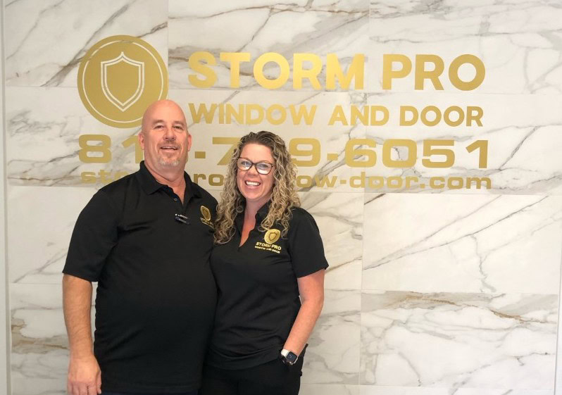 Storm Pro Window and Door team in front of the showroom logo wall