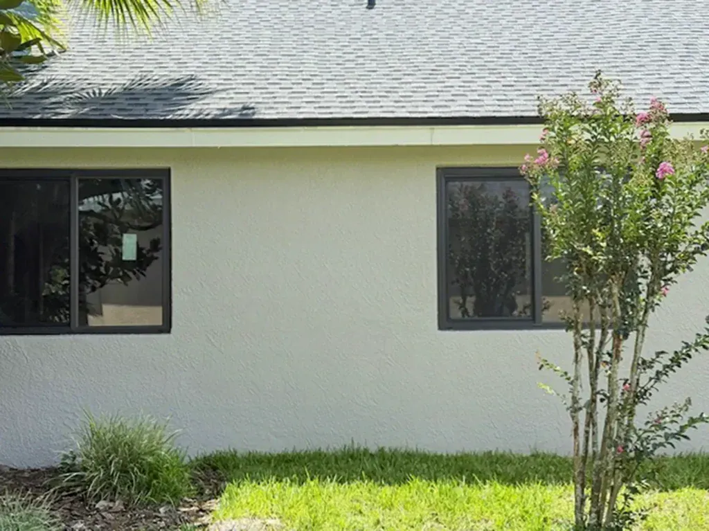 Dark-framed impact windows on a stucco home, an alternative to hurricane shutters