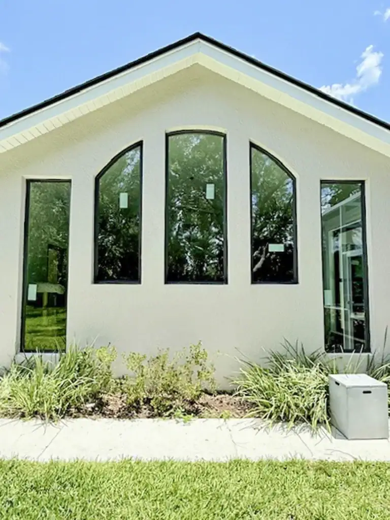 Dark-framed arched and rectangular windows beneath a gabled roof