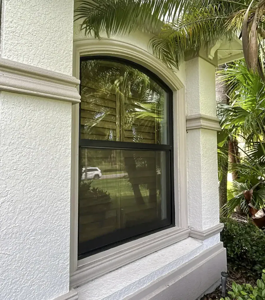 Black arched window surrounded by decorative stucco trim