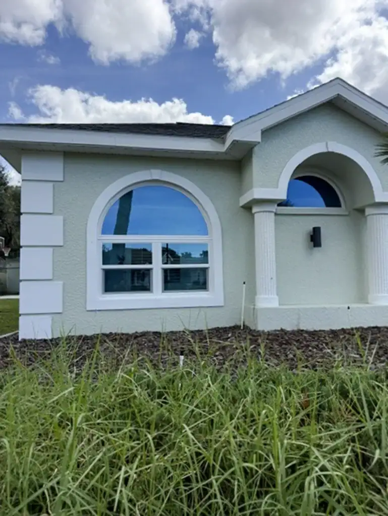 White-framed arched window on a light stucco home