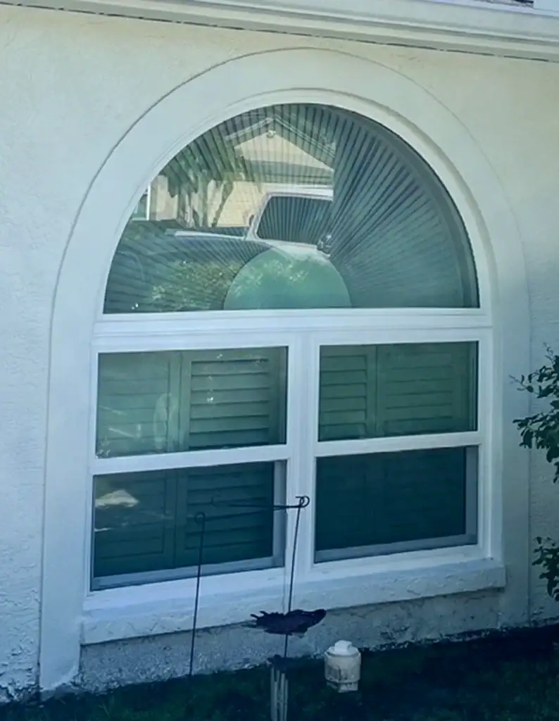 White arched window with divided lights on a stucco exterior