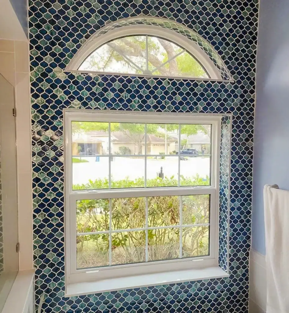 White bathroom window with an arched transom and patterned tile surround