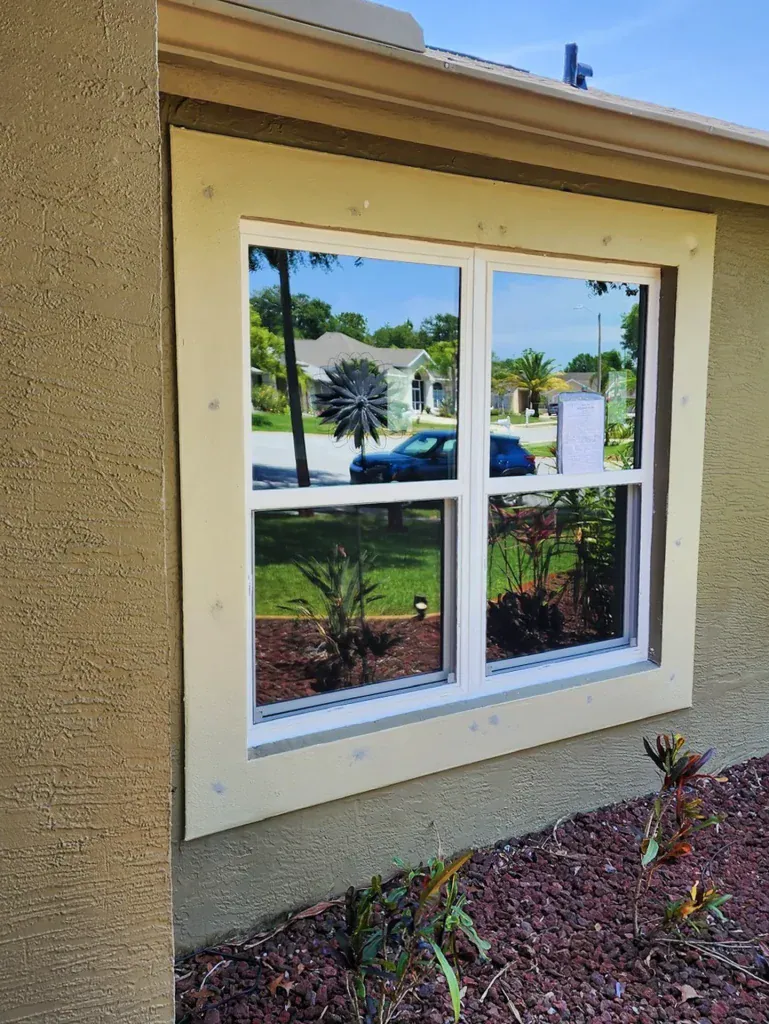 White divided-light window on a tan stucco exterior
