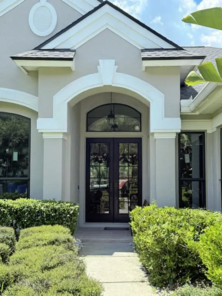 Dark double entry doors and an arched transom at a landscaped entrance