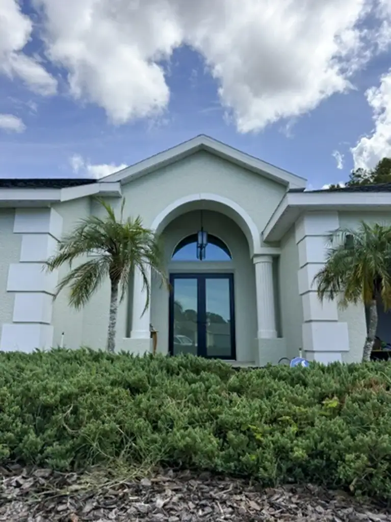Glass entry doors beneath an arched transom on a stucco home