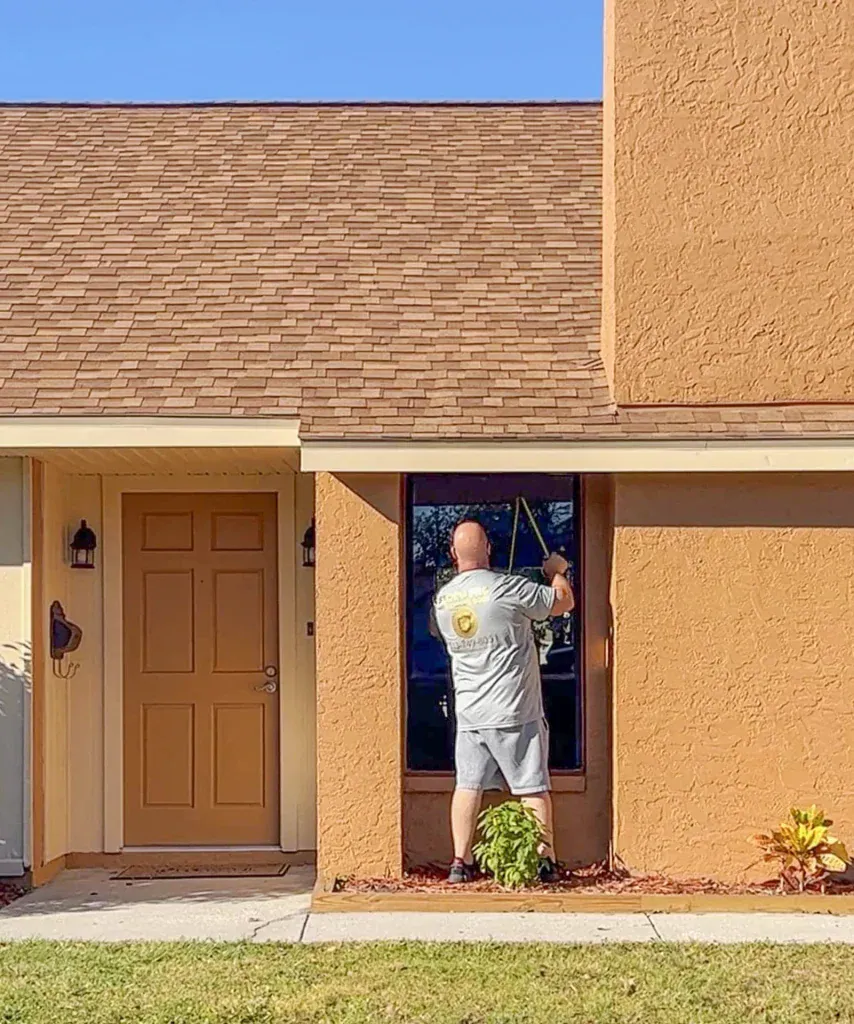 Installer preparing a window opening on an orange stucco home