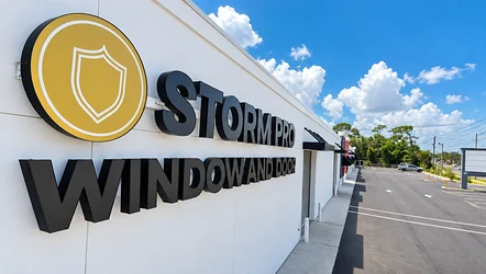 Storm Pro Window and Door sign on the Tarpon Springs showroom under a blue Florida sky