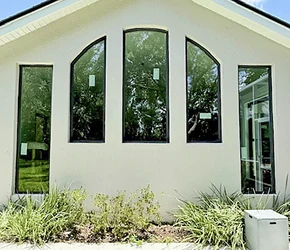 Arched and picture impact windows on a stucco gable wall installed by Storm Pro