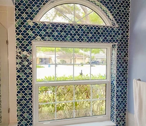 Impact bathroom window with arched transom in a tiled wall installed by Storm Pro