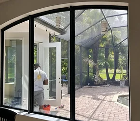 Black arched impact casement windows open to a screened lanai