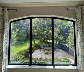 Black-frame arched impact window group viewed from inside a Florida home