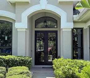 Impact double entry doors under an arched transom on a stucco home