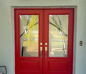 Red impact double entry doors with decorative glass and arched transom installed by Storm Pro