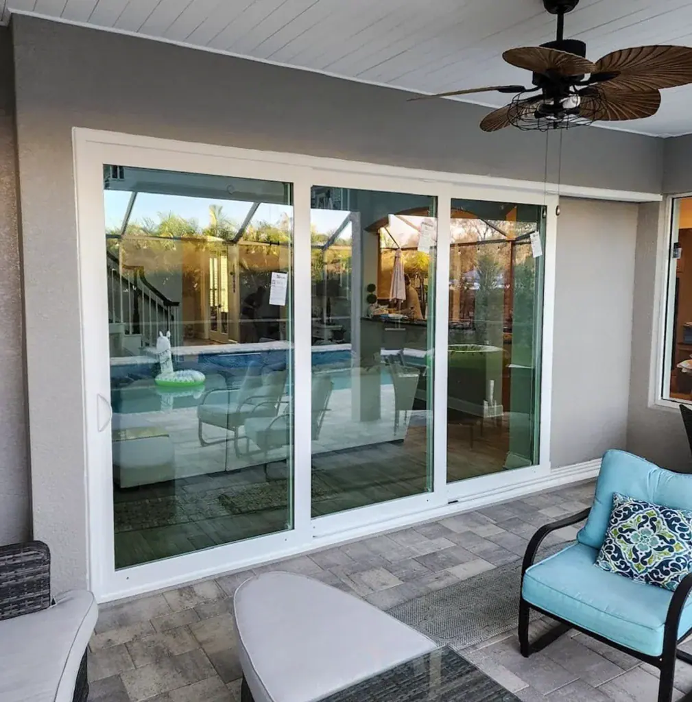 White sliding glass doors viewed from a covered outdoor sitting area