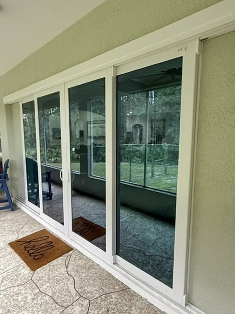 White sliding glass doors viewed from a screened lanai
