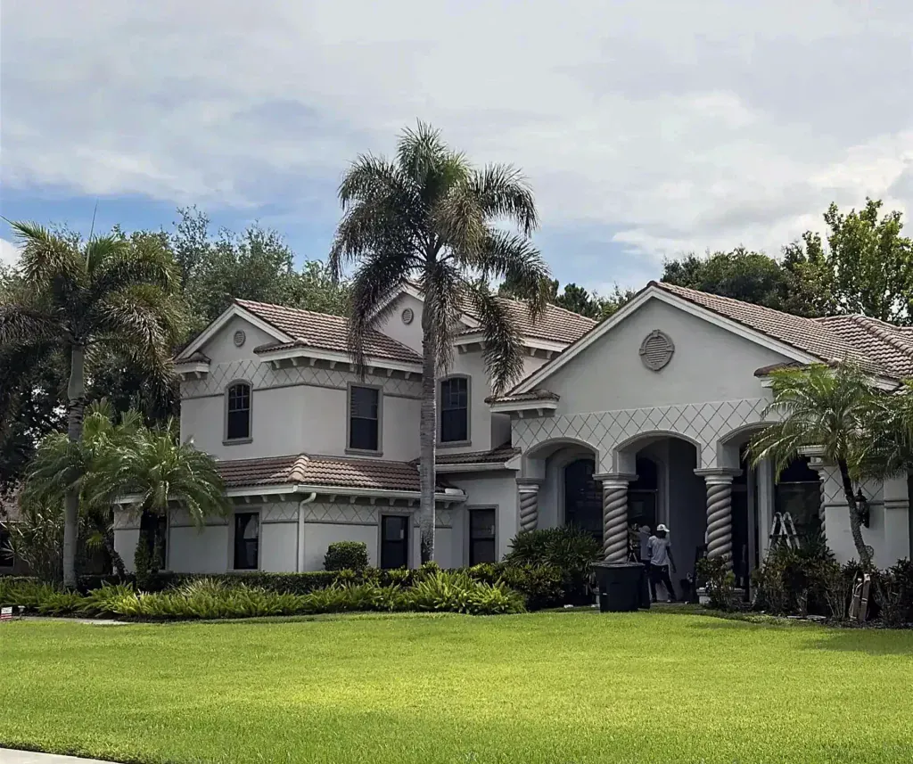 Two-story stucco home with dark-framed windows and a landscaped lawn