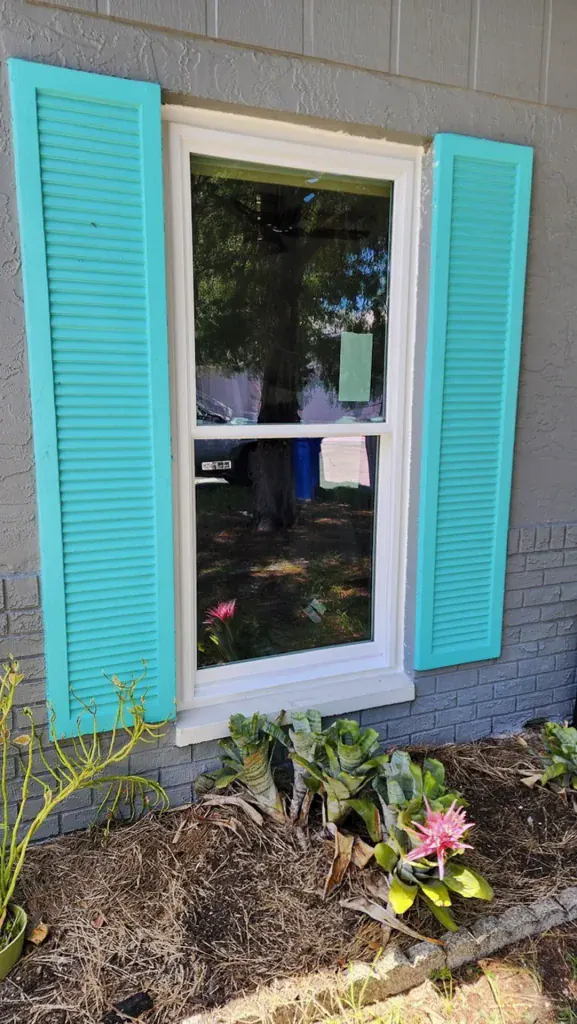 White window framed by turquoise exterior shutters