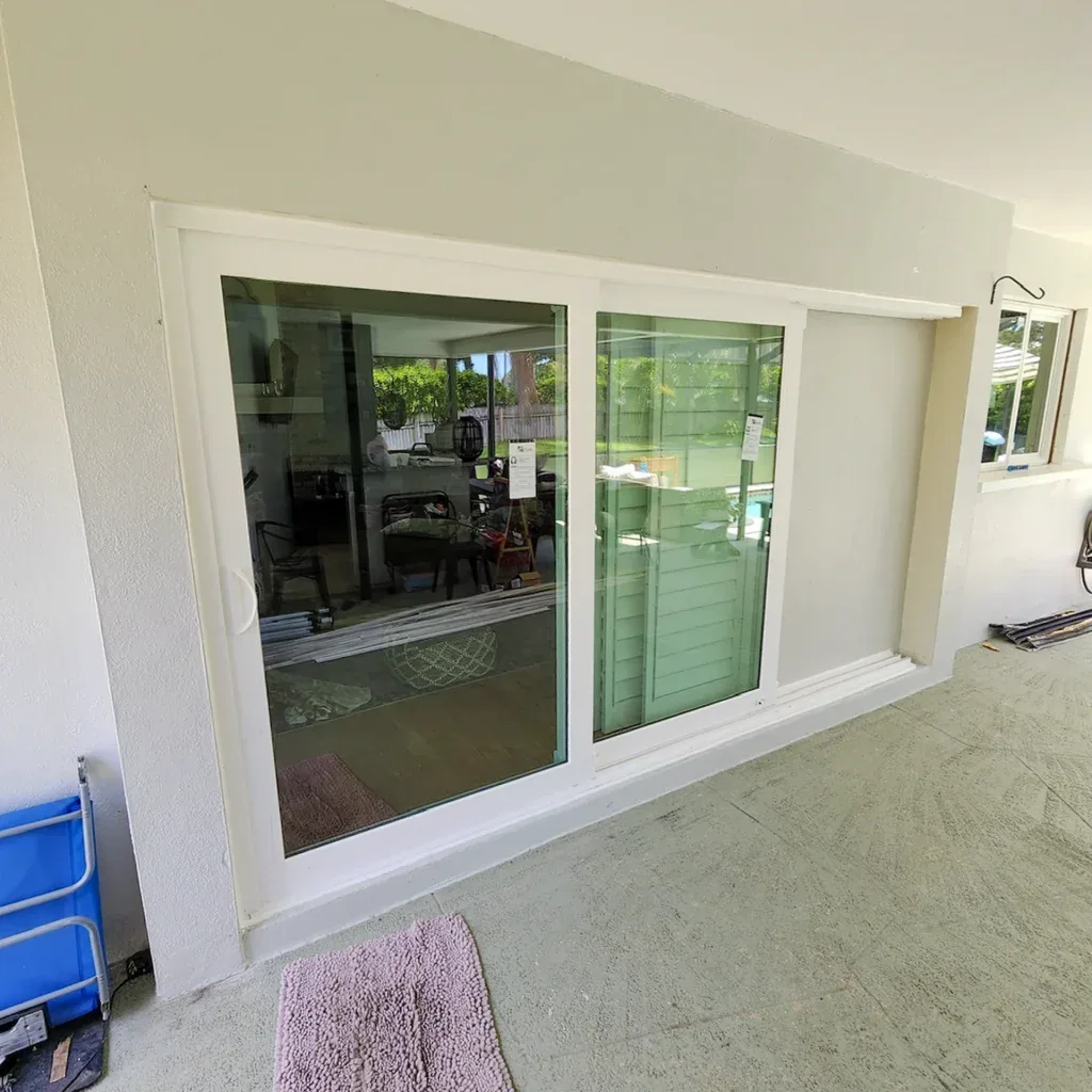 Wide white sliding glass doors on a covered patio